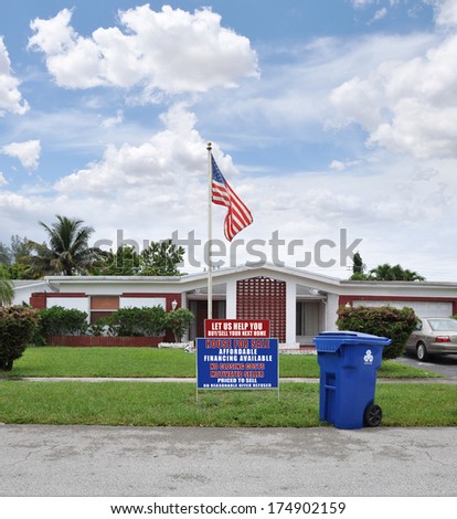 American Flag Pole Real Estate For Sale Recycle Trash Container Suburban ranch style home sunny blue sky clouds day residential neighborhood USA