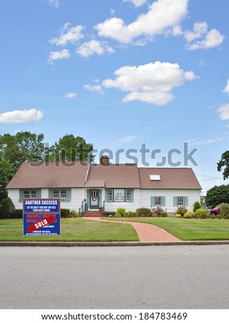 Real Estate Sold (Another success let us help you buy sell your next home) sign Suburban Ranch style home brick walkway blue sky clouds residential neighborhood USA