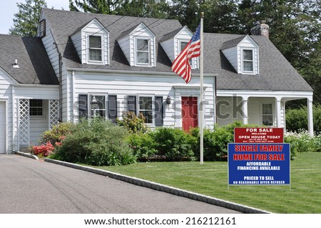 Real Estate For Sale Open House Welcome Sign and American Flag Pole on front yard lawn of Suburban Cape Cod Colonial Style Home Sunny Residential Neighborhood USA