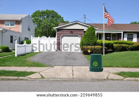 American Flag pole recycle trash container driveway entrance suburban home residential neighborhood USA clear blue sky