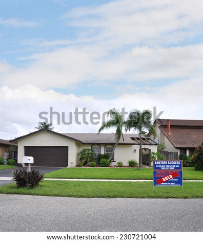 Sold real estate (another success let us help you buy sell your next home) sign suburban ranch style home residential neighborhood blue sky clouds USA