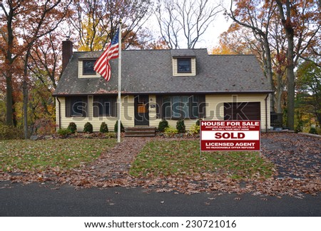 American flag pole Real Estate Sold (another success let us help you buy sell your next home) on autumn leaves front yard of suburban cape cod style home fall season residential neighborhood sky USA
