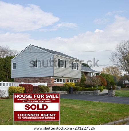 Real estate sold (another success let us help you buy sell your next home) on lawn of suburban high ranch style home autumn season residential neighborhood blue sky clouds USA