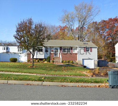 Suburban bungalow home trash can curbside autumn day residential neighborhood blue sky USA