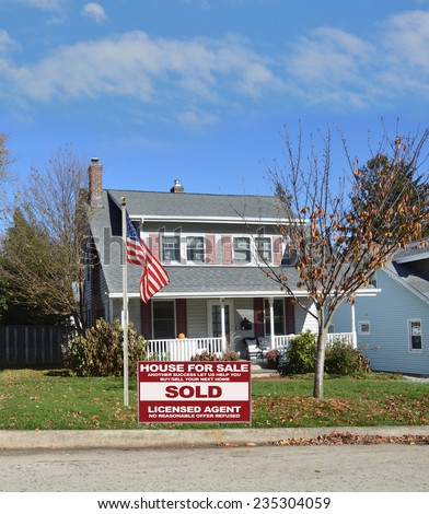 American flag pole Real Estate Sold (another success let us help you buy sell your next home) sign suburban bungalow style home autumn day residential neighborhood blue sky USA