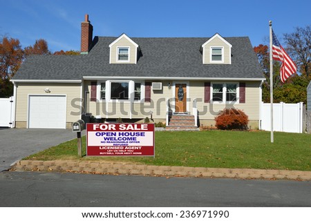 American Flag pole Real Estate for sale open house welcome sign Suburban cape cod style home autumn day residential neighborhood clear blue sky USA