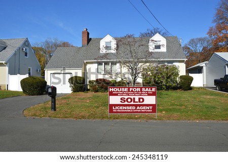 Real Estate Sold (another success let us help you buy sell your next home) sign Suburban Cape Cod home autumn day residential neighborhood Sunny Clear Blue Sky Day USA