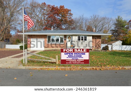 American flag pole Real estate for sale open house welcome sign suburban brick ranch style coral fence cement driveway home autumn blue sky day residential neighborhood USA