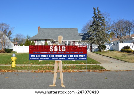 Mannequin holding Real estate sold (another success let us help you buy sell your next home) sign Suburban brick and siding cape cod style home fire hydrant curbside on autumn residential zone USA