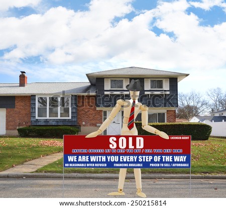 Mannequin wearing red tie holding Real estate sold (another success let us help you buy sell your next home) sign Suburban high ranch brick home autumn blue sky clouds day residential neighborhood USA