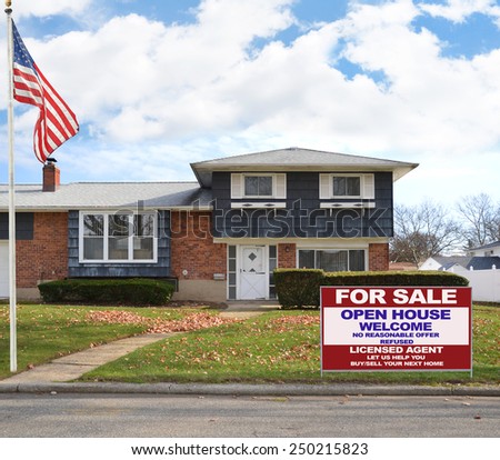 American flag pole Real estate for sale open house welcome sign Suburban high ranch brick home autumn blue sky clouds day residential neighborhood USA