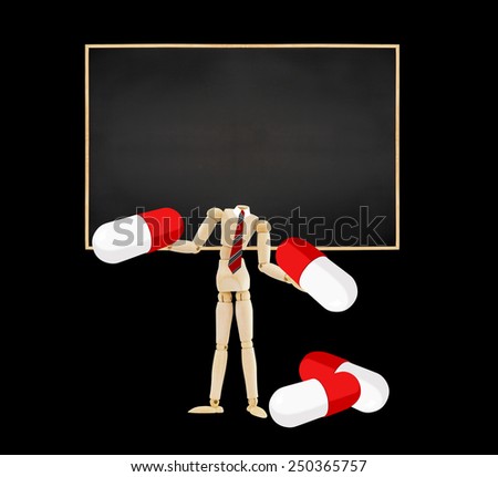 Mannequin without head holding prescription medication pills standing in front of blank blackboard isolated on black background