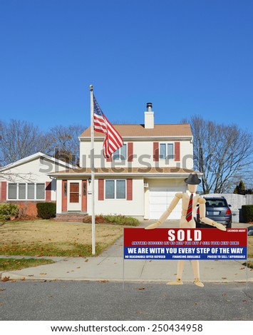 American flag pole flag pole mannequin wearing businessman attire holding Real estate sold (another success let us help you buy sell your next home) sign Suburban home  residential neighborhood  USA