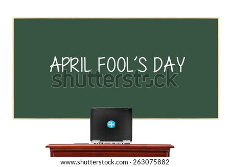 Chalkboard with April Fool\'s Day behind desk with computer Prankster sticker button isolated on white background