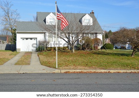 American Flag pole Suburban Cape Cod style home sunny blue sky autumn day residential neighborhood USA
