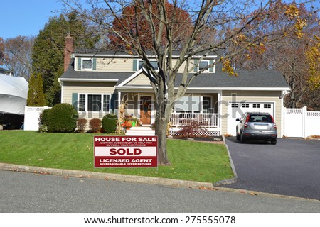Real estate sold (another success let us help you buy sell your next home) sign Suburban Cape Cod style home autumn clear blue sky day residential neighborhood USA