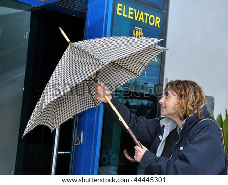 Latin woman closing her umbrella as she walks into her office building