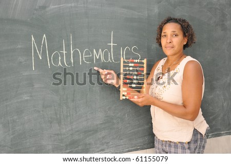 Mature African American Woman Teacher at Blackboard in Elementary School Classroom