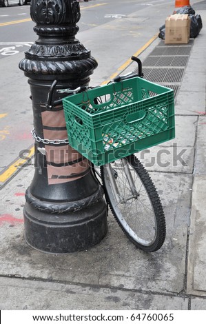 Bicycle on urban grungy dirty sidewalk locked to Lamp post in Brooklyn New York