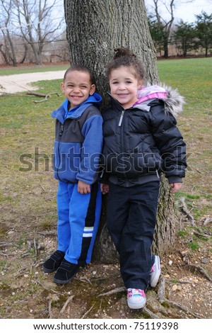 Smiling Preschool Age Children Standing Outside by Tree in Nature Park Family