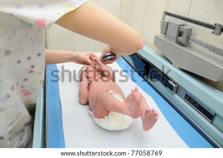 Newborn Infant Baby on Pediatric Scale Table Getting Head Measured by Nurse in Medical Office