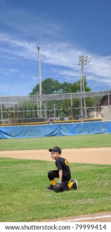 Boy Short Stop Kneeling on Field Waiting for Ball wearing uniform and glove