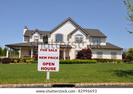 Real Estate For Sale Sign on Lawn of Large Suburban Home Residence on Sunny Day