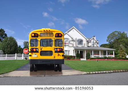 School Bus with Stop Sign Extended Handicap Symbol in Window Waiting in Driveway of Luxury Suburban Home