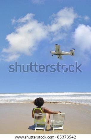 Airplane Flying over Woman Sitting on Vacation on Mediterranean Beach in Costa Blanca Alicante Spain Europe