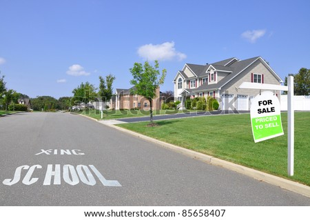 School Crossing Street Sign Real Estate For Sale Sign on Front Yard Lawn of Luxury Suburban Home in Residential District on Sunny Blue Sky Day