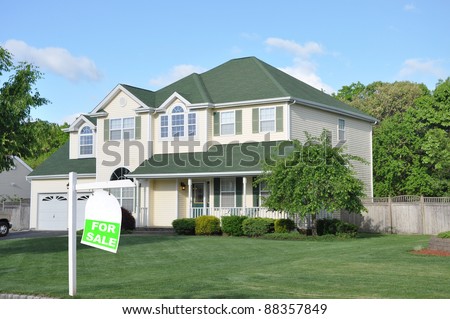 Realtor For Sale Sign on landscaped front yard lawn of large suburban home in residential neighborhood