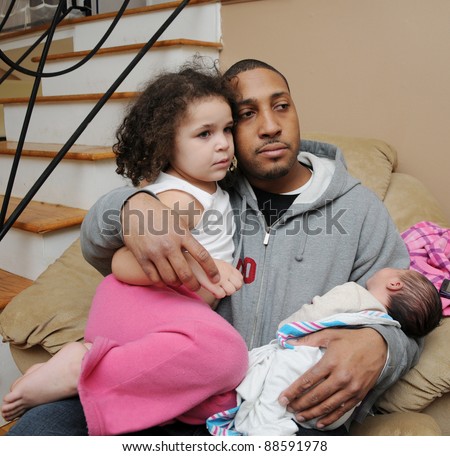 Loving Two Generation Family Newborn Infant in arms of Father holding Daughter on Lap Hugging looking away