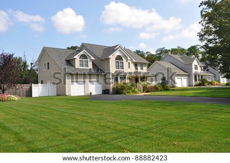 Large Suburban Cape Cod McMansion Home in Residential District Daytime Blue Cloud Sky