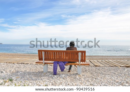 Woman sitting on Wood Bench along Beach Path in Villa Joyosa Spain a town in the province of Alicante in late afternoon