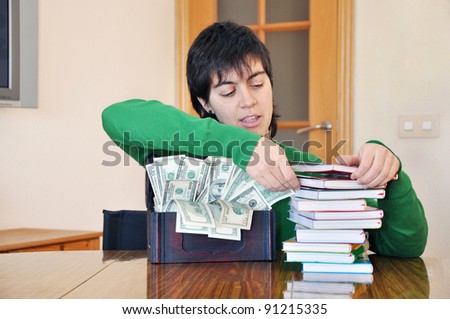 College Grad Student reviewing books next to box of money