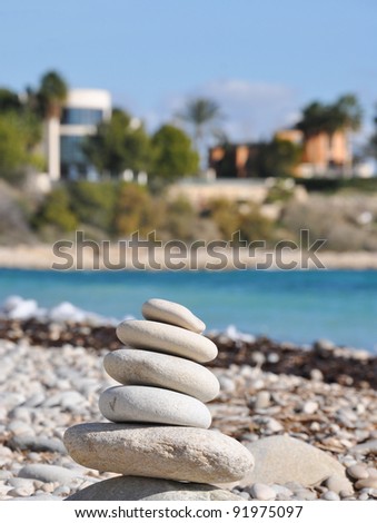 Zen Like Meditation Stone Tower on Rocky Beach with Architecture and Sea in Background