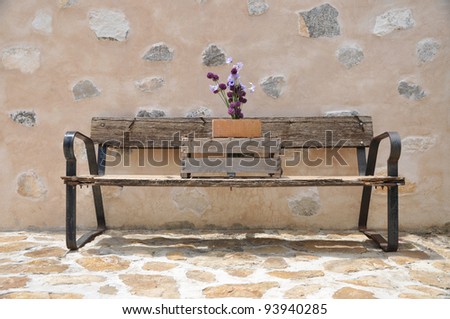 Old Wood Bench with Booming Garlic Flowers and Daisies outside rock stone patio