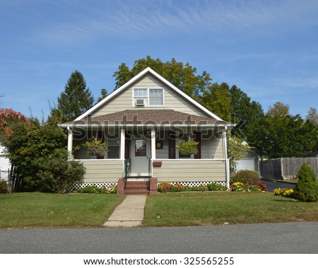 Suburban Tan Bungalow Home with brick steps, yellow and orange mums and marigold flowers residential neighborhood USA