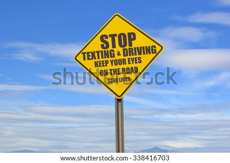 Stop Texting & Driving Keep Your Eyes on the Road Save Lives Yellow Traffic Sign blue sky clouds tips of mountains