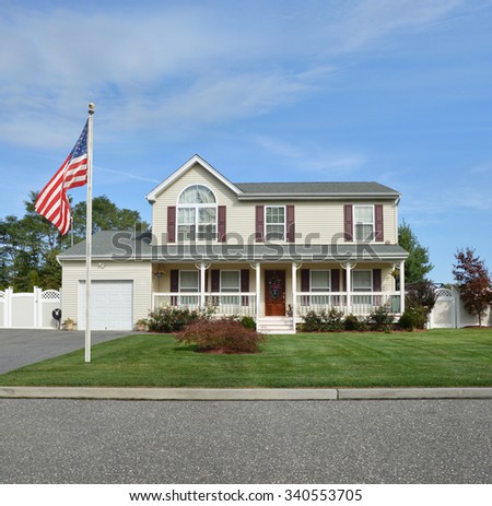 American Flag pole Beautiful Suburban McMansion Home Landscaped blue sky clouds residential neighborhood USA