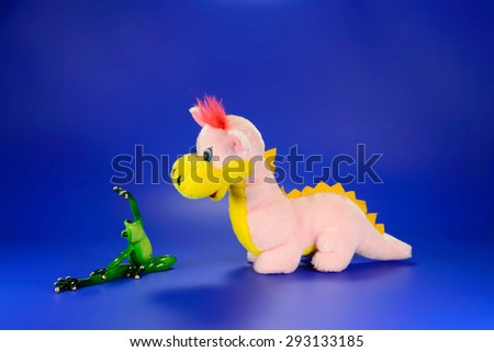 Pink dragon toy with a green frog on a blue background