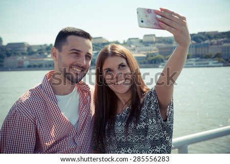 The young guy and the attractive woman take a selfie next to the Danube