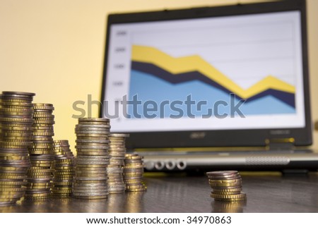 Saved coins in front of a computer showing bad financial data