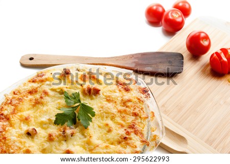 Baked squash with meat, cherry tomatoes and herbs in a glass pot. Wooden cutting board. Closeup studio shot