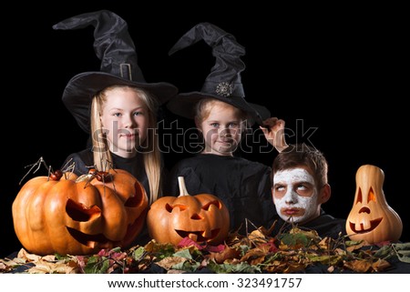 Halloween. Two little witches, skull surrounded by pumpkins,  foliage and spiders on a black background. Teens fun