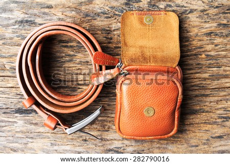 Brown leather bag, box with belt on wood