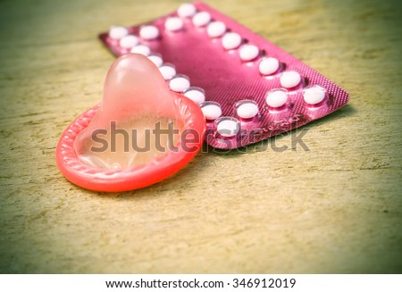 birth control pills and condom on wooden table background.soft and selective focus  vintage color tone with filter color effect.
