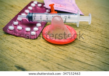condom and birth control pills on wooden table background.soft and selective focus. vintage color tone.