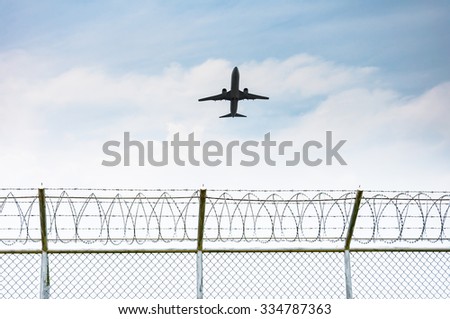 Airplane taking off from the airport over the fence of high security zone in Phuket , Thailand