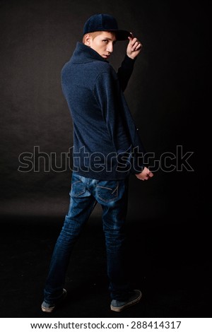 boy dressed casually in a studio on a black background in back
